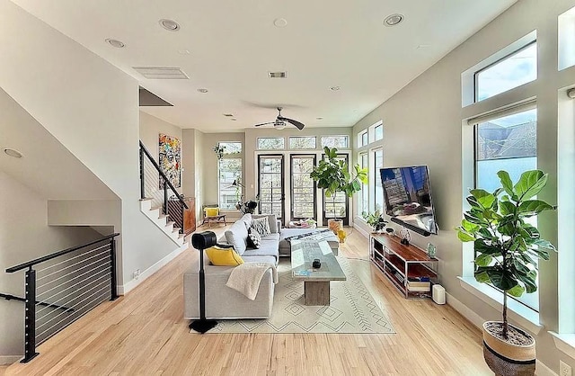 living area featuring a ceiling fan, visible vents, stairway, and light wood-style floors
