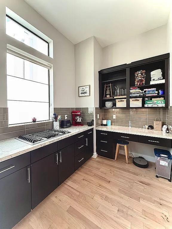 kitchen with stainless steel gas stovetop, dark cabinets, tasteful backsplash, and open shelves