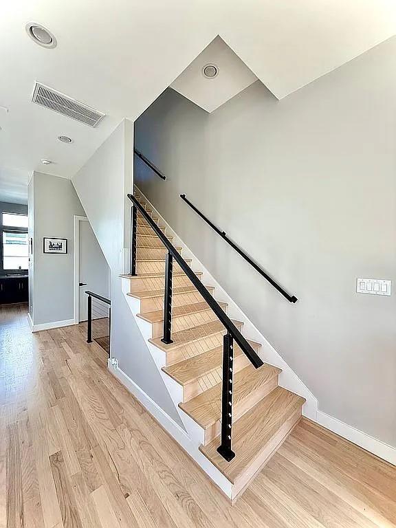 stairway featuring baseboards, visible vents, and wood finished floors
