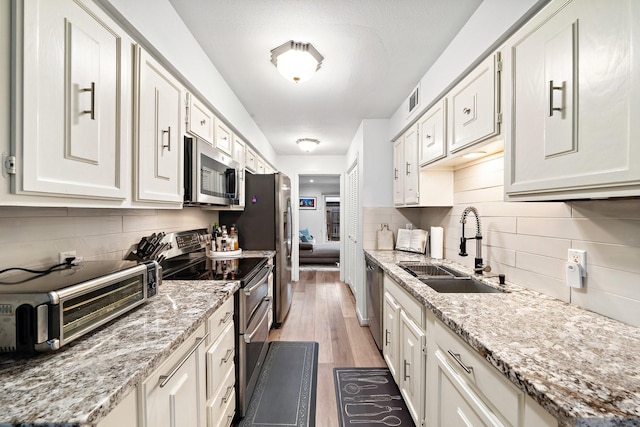 kitchen featuring appliances with stainless steel finishes, a sink, decorative backsplash, a toaster, and visible vents
