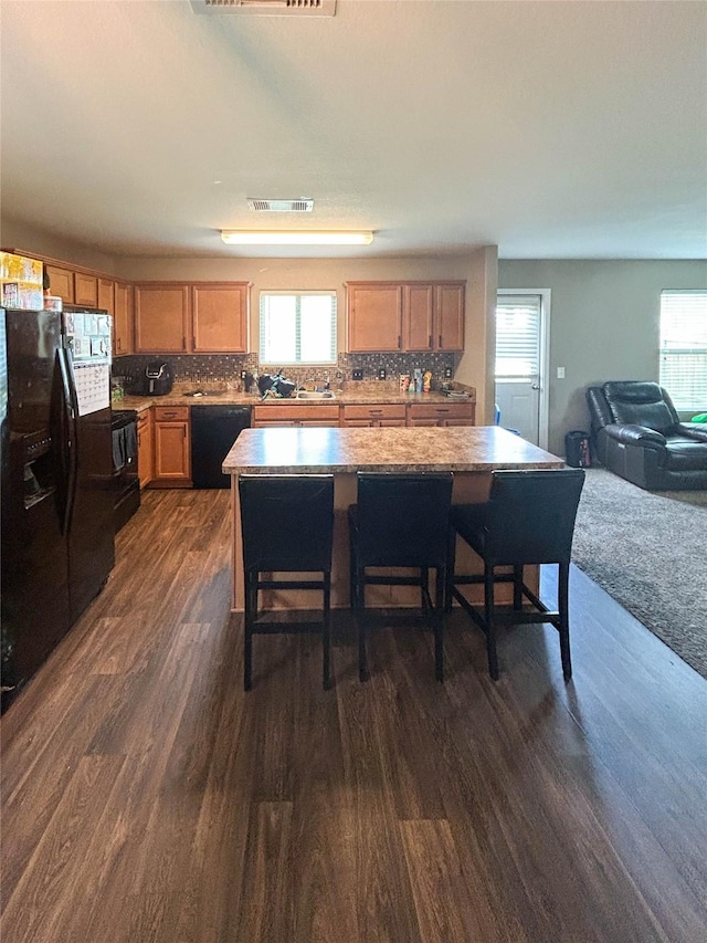 kitchen featuring dark wood-type flooring, black appliances, a wealth of natural light, and visible vents