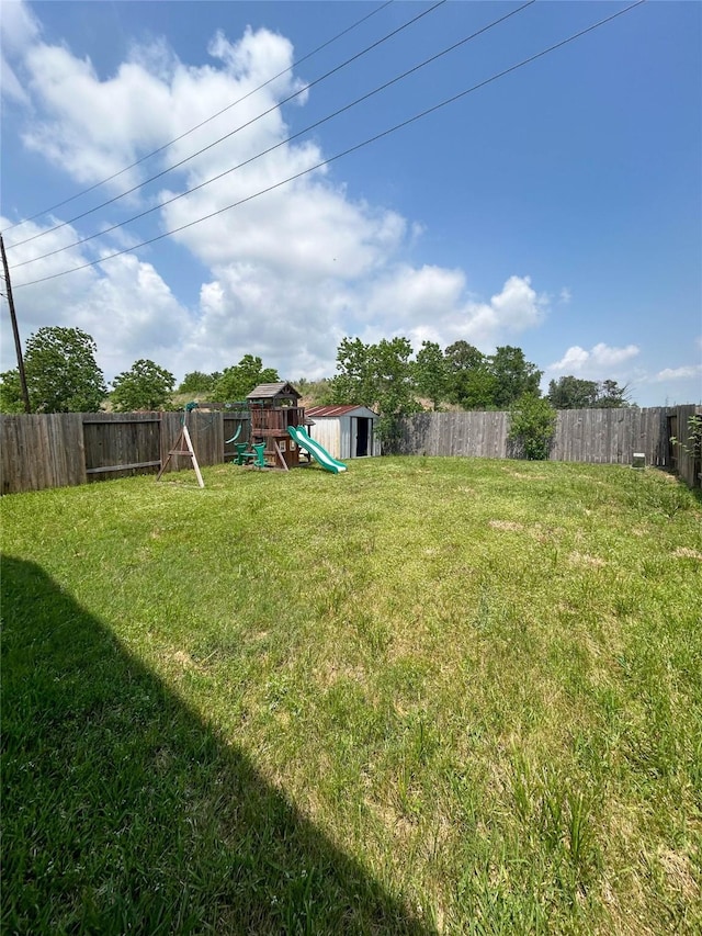 view of yard with a playground, an outbuilding, a fenced backyard, and a storage shed