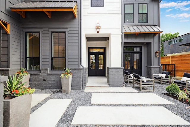 entrance to property with french doors, fence, a standing seam roof, and metal roof
