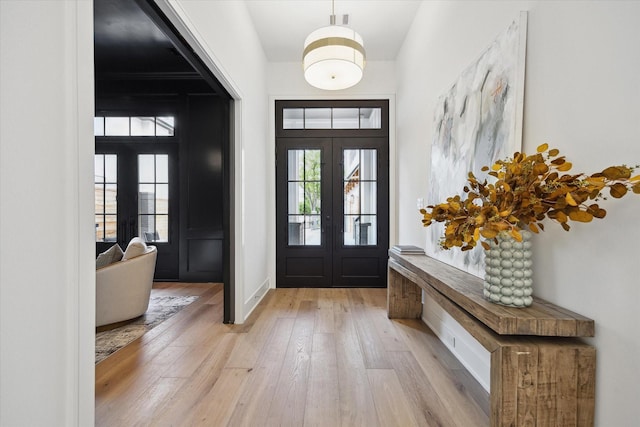 entryway with baseboards, french doors, and light wood-type flooring