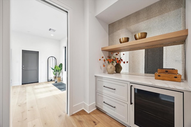 bar with decorative backsplash, visible vents, baseboards, wine cooler, and light wood-style flooring