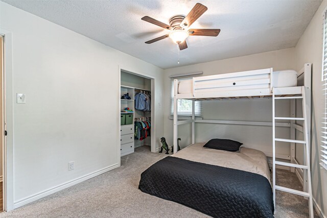 carpeted bedroom with a closet, baseboards, and a ceiling fan