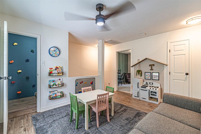 playroom with a ceiling fan, baseboards, visible vents, and wood finished floors