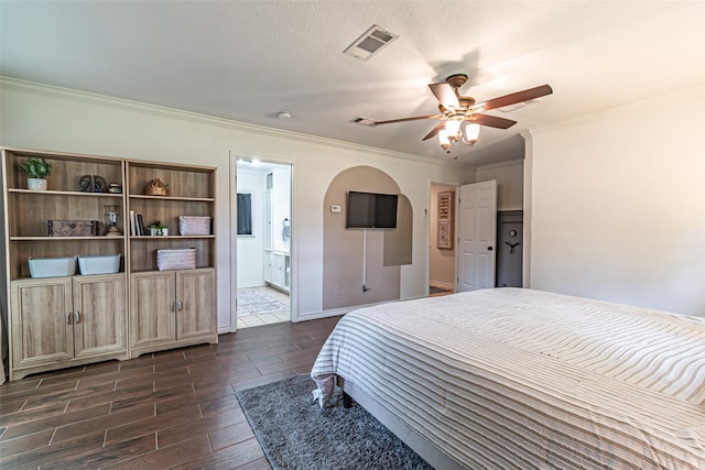 bedroom with visible vents, dark wood finished floors, crown molding, and ensuite bath