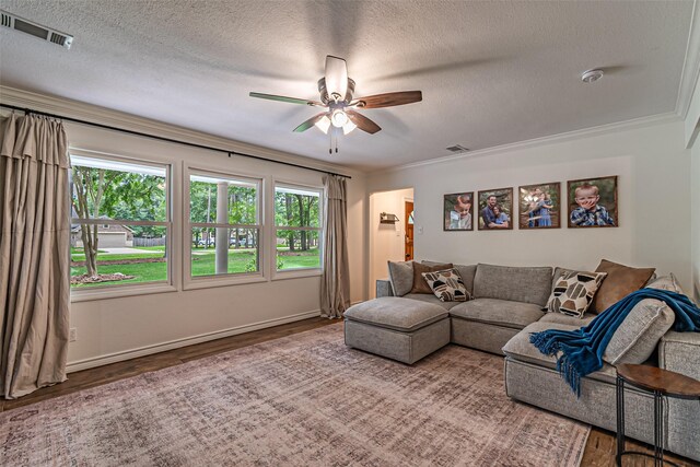 living room with a textured ceiling, ceiling fan, visible vents, and wood finished floors