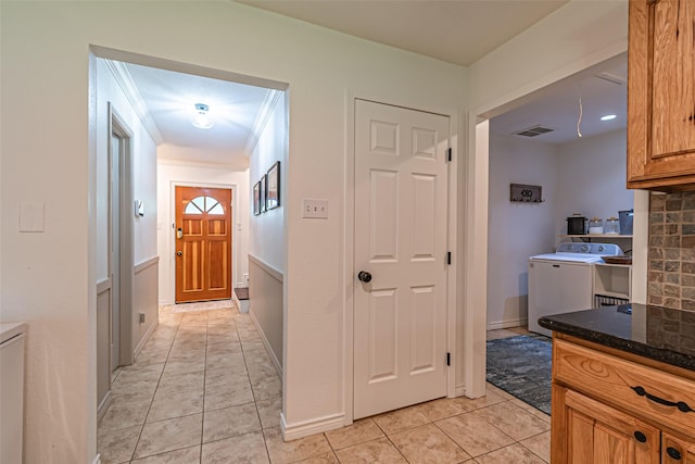 corridor featuring washer / clothes dryer, visible vents, light tile patterned floors, baseboards, and ornamental molding