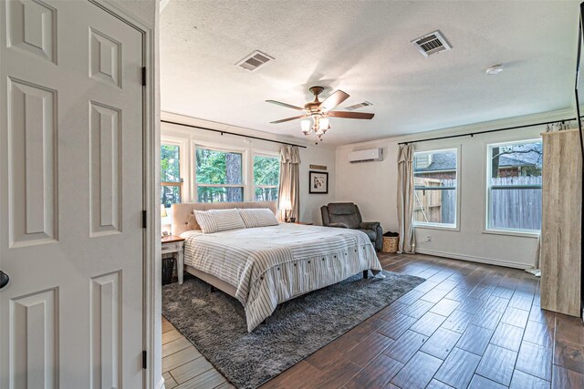 bedroom featuring a wall unit AC, wood finished floors, and visible vents