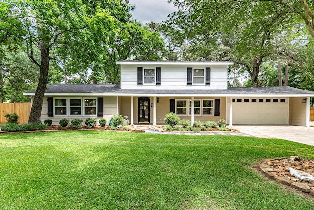 traditional-style house featuring fence, a front lawn, concrete driveway, an attached garage, and a shingled roof