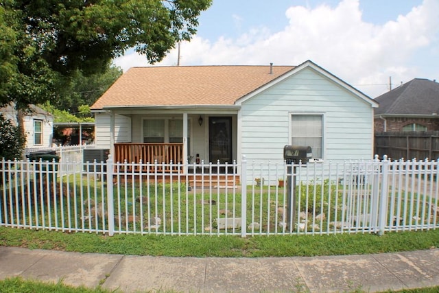 bungalow-style home with covered porch, a fenced front yard, a shingled roof, and a front yard