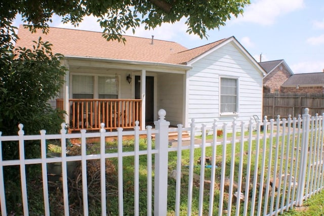 bungalow-style house with a porch, a shingled roof, fence private yard, and a front lawn