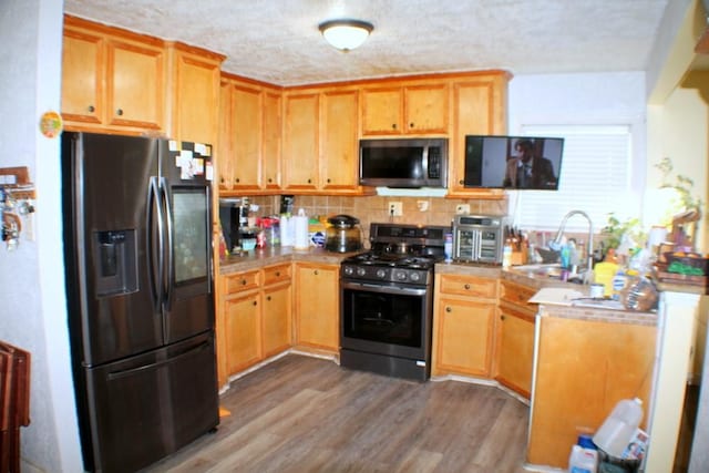 7721 Brumblay St, Houston, TX 77012 - kitchen with a textured ceiling, dark wood finished floors, a sink, stainless steel appliances, and tasteful backsplash
