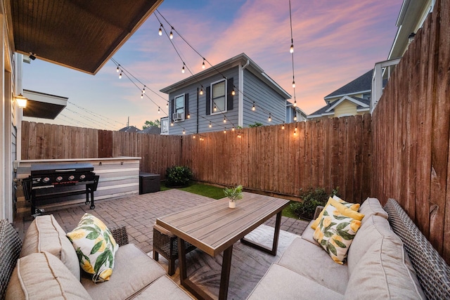 patio terrace at dusk featuring a fenced backyard, cooling unit, outdoor lounge area, and outdoor dining space