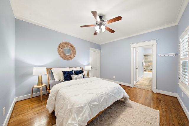 bedroom featuring a ceiling fan, crown molding, wood finished floors, baseboards, and ensuite bathroom