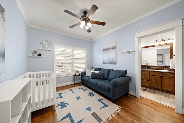 bedroom featuring crown molding, a sink, and light wood-style flooring