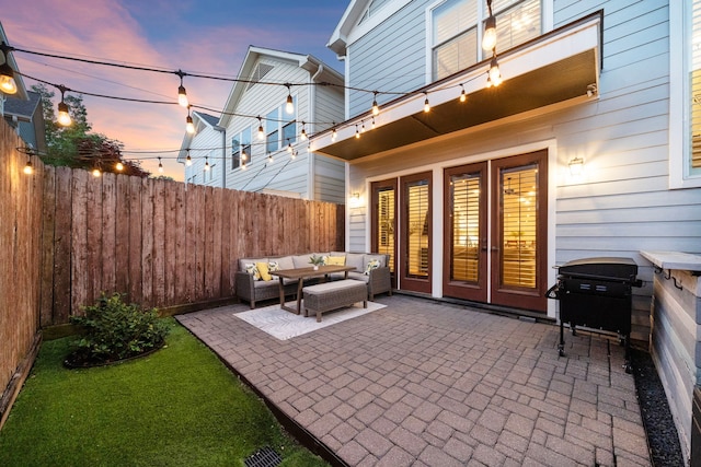 patio terrace at dusk featuring a fenced backyard and an outdoor living space