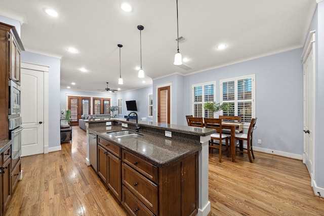 kitchen featuring a sink, light wood-style flooring, appliances with stainless steel finishes, and ornamental molding