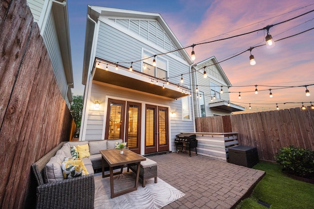rear view of house featuring fence, a balcony, a patio, french doors, and an outdoor hangout area