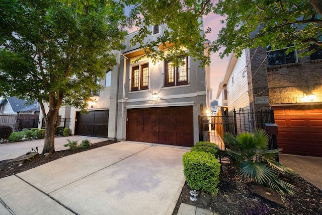 view of front facade featuring fence, an attached garage, stucco siding, and concrete driveway