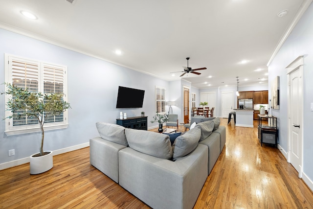 living area with ceiling fan, crown molding, baseboards, recessed lighting, and light wood-style flooring
