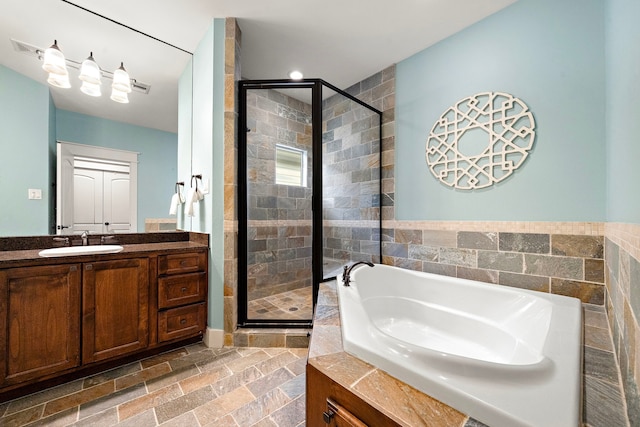 bathroom featuring vanity, a shower stall, visible vents, a garden tub, and stone tile flooring