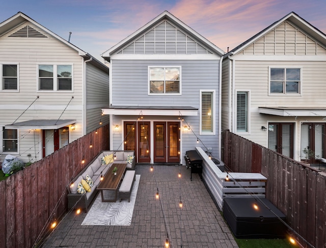 back of property at dusk featuring a fenced backyard, a patio, and outdoor lounge area