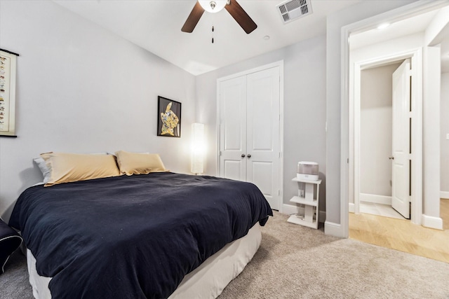 bedroom featuring visible vents, a closet, light carpet, baseboards, and a ceiling fan