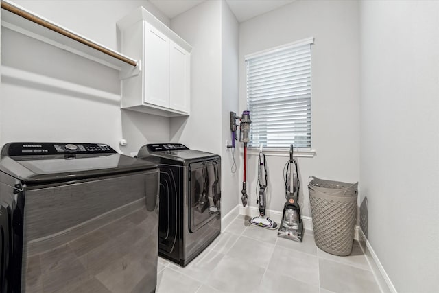 washroom featuring baseboards, cabinet space, independent washer and dryer, and light tile patterned floors