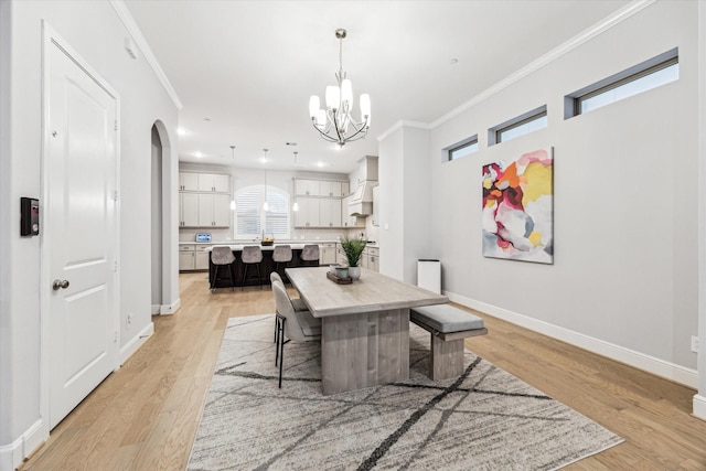 dining area with crown molding, arched walkways, baseboards, and a chandelier