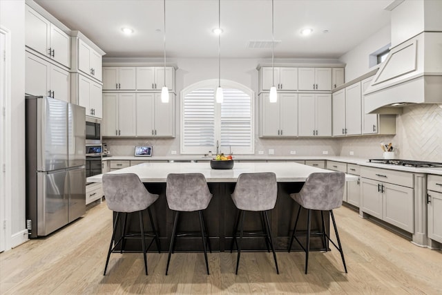 kitchen with backsplash, a kitchen island, visible vents, appliances with stainless steel finishes, and light countertops