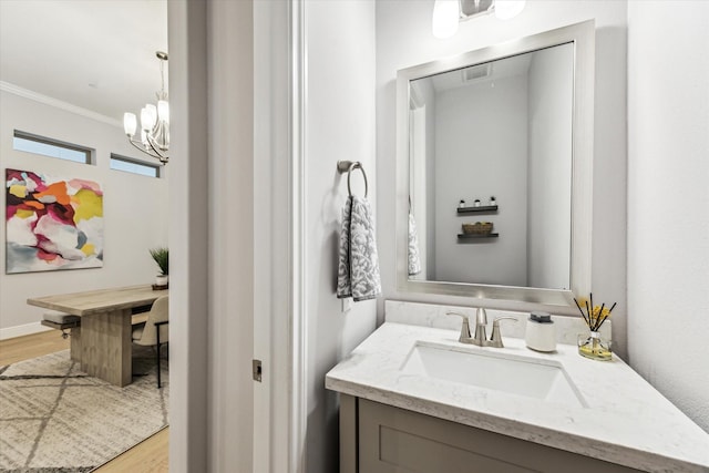 bathroom featuring a chandelier, ornamental molding, wood finished floors, and vanity