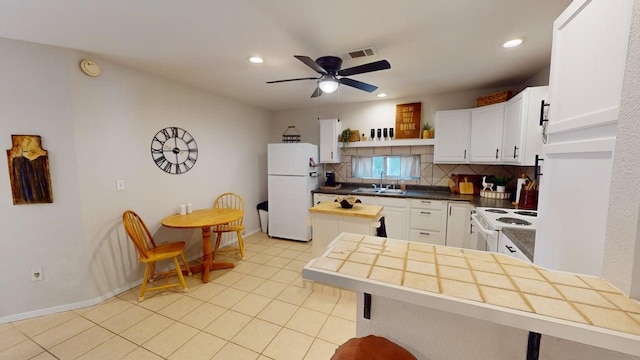 kitchen featuring decorative backsplash, visible vents, a sink, white cabinets, and white appliances