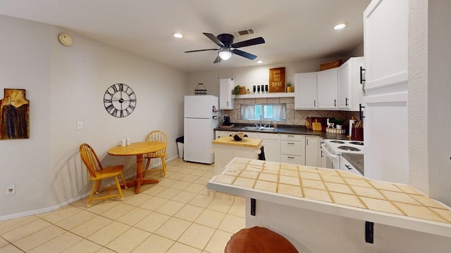 kitchen featuring visible vents, decorative backsplash, a peninsula, white appliances, and a sink