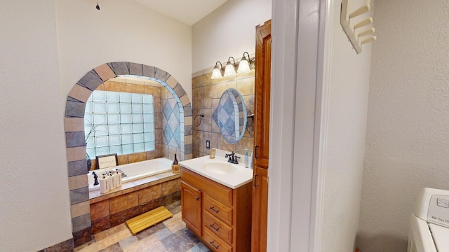 full bathroom featuring vanity, washer / clothes dryer, and a bath