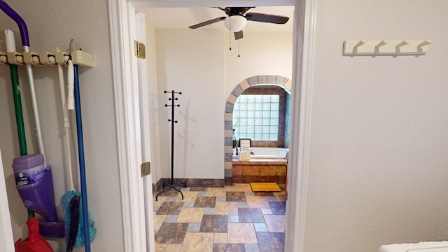 hall with baseboards, arched walkways, and stone finish flooring