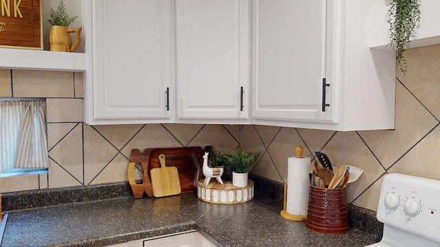 interior details featuring dark countertops, white cabinets, and backsplash