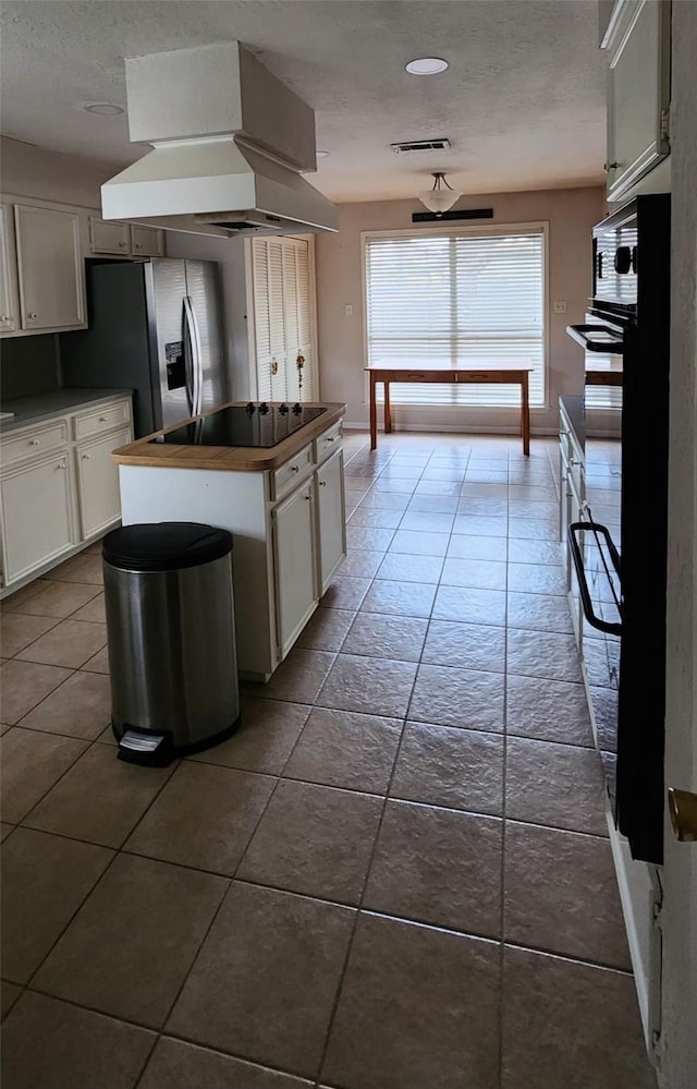 532 S Rivershire Dr, Conroe, TX 77304 - kitchen featuring black electric stovetop, a textured ceiling, island exhaust hood, white cabinets, and dark tile patterned flooring