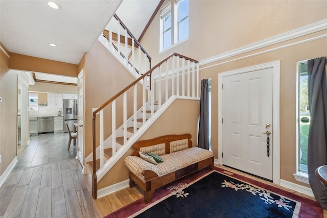 foyer entrance with baseboards, recessed lighting, light wood finished floors, and stairway