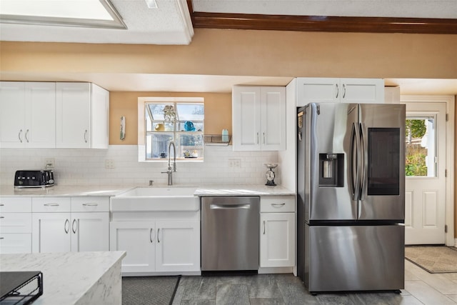 kitchen with a sink, appliances with stainless steel finishes, white cabinets, and decorative backsplash