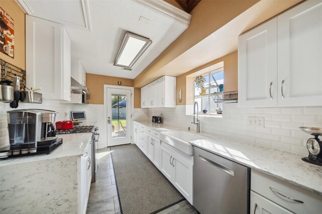 kitchen featuring exhaust hood, stainless steel appliances, decorative backsplash, and a sink