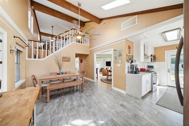 dining room featuring beam ceiling, high vaulted ceiling, stairs, a ceiling fan, and visible vents