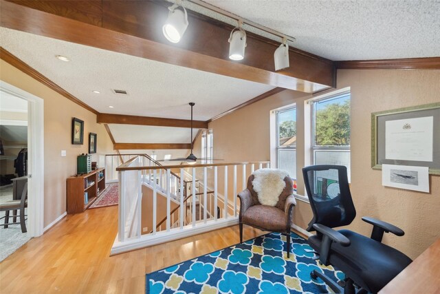 living area with a textured ceiling, visible vents, wood finished floors, an upstairs landing, and ornamental molding