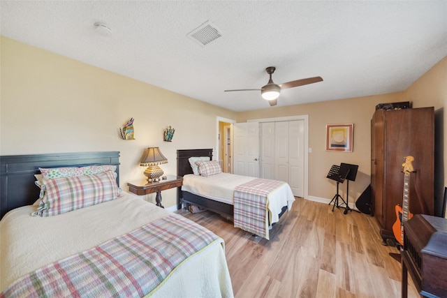 bedroom with ceiling fan, visible vents, baseboards, a closet, and light wood-style floors