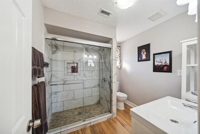 full bath featuring a stall shower, toilet, wood finished floors, and visible vents