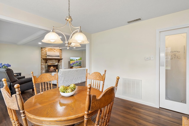 dining area with a fireplace, beamed ceiling, dark wood-type flooring, and visible vents