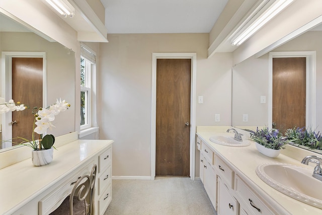 bathroom with double vanity, a sink, and baseboards