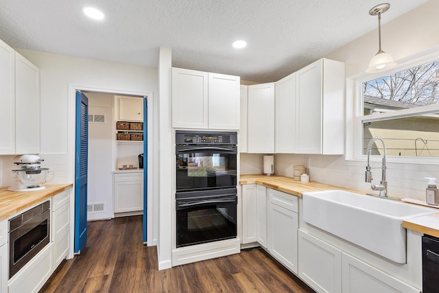 kitchen featuring butcher block countertops, a sink, stainless steel microwave, and dobule oven black